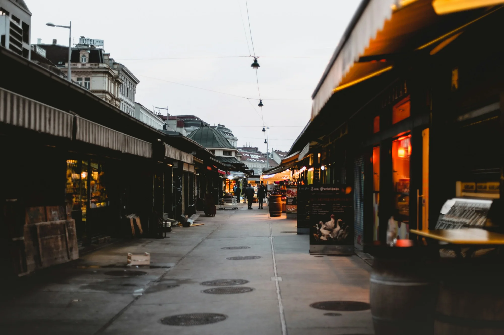 A lively alley in Vienna's Naschmarkt, featuring illuminated stalls and shops.