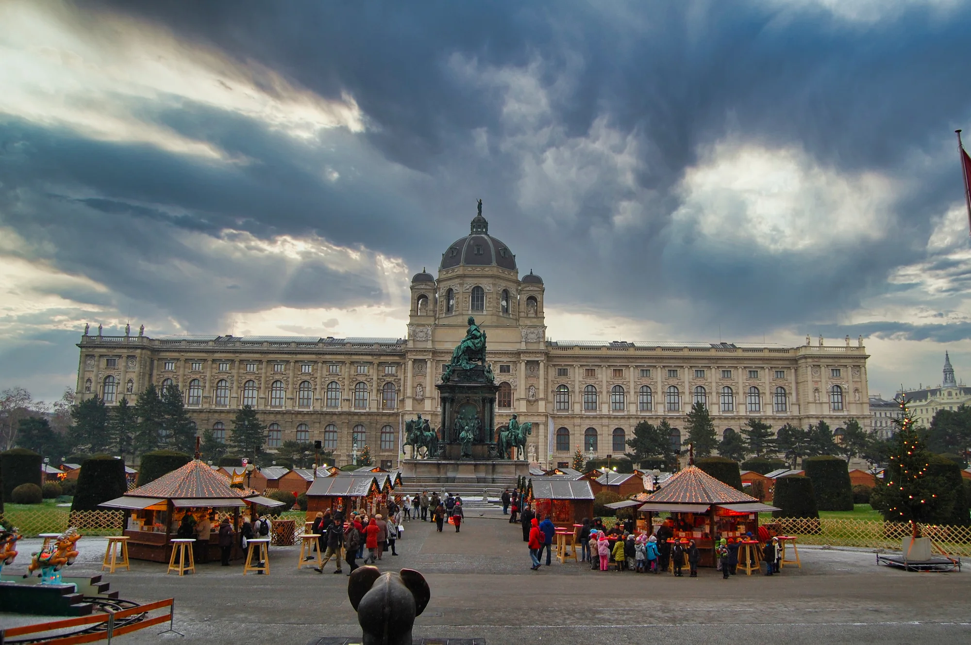 Kunsthistorisches Museum in Vienna exterior with markets and dramatic sky.
