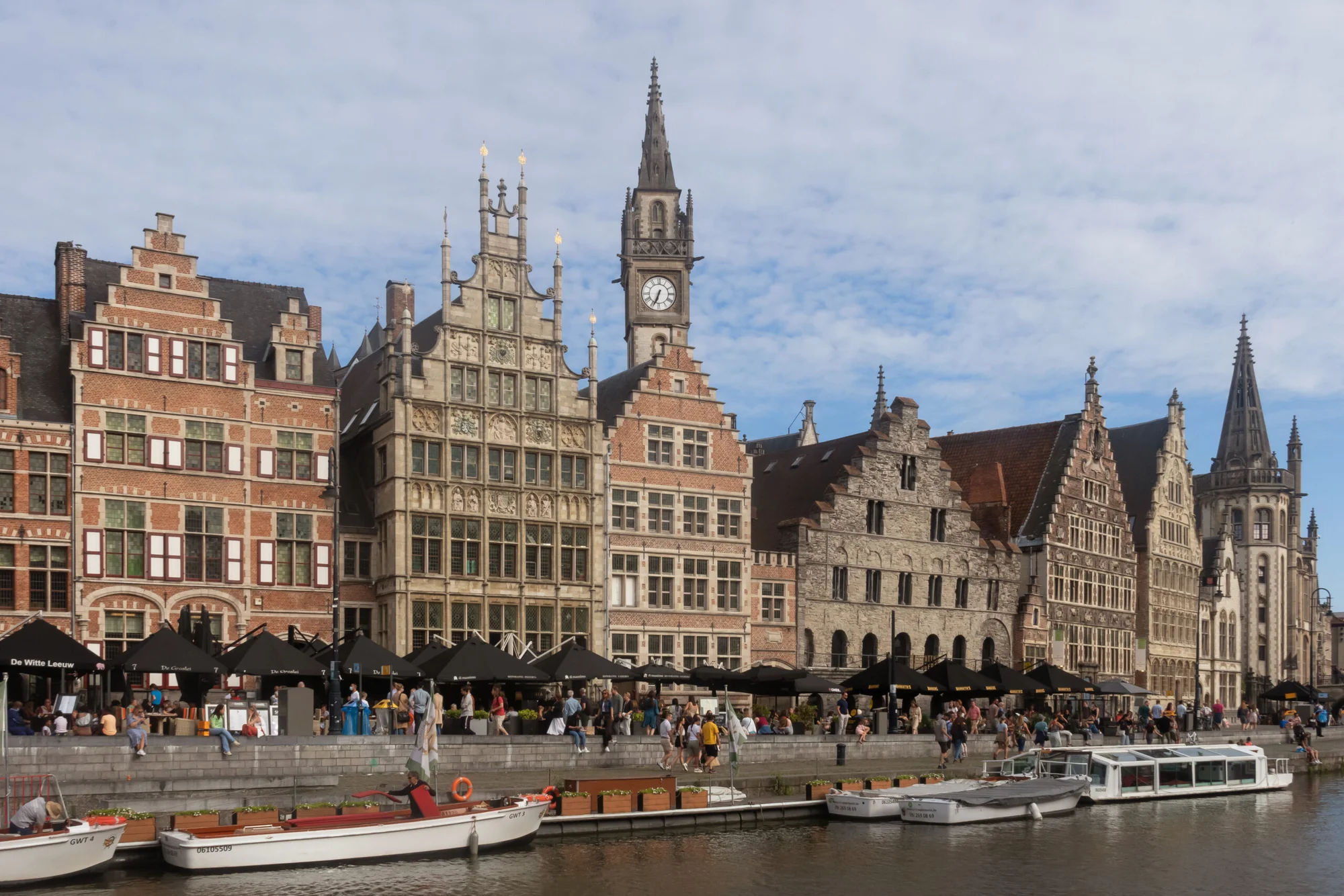 Historic houses and spires at Graslei and Korenlei, Ghent, with boats on the canal.