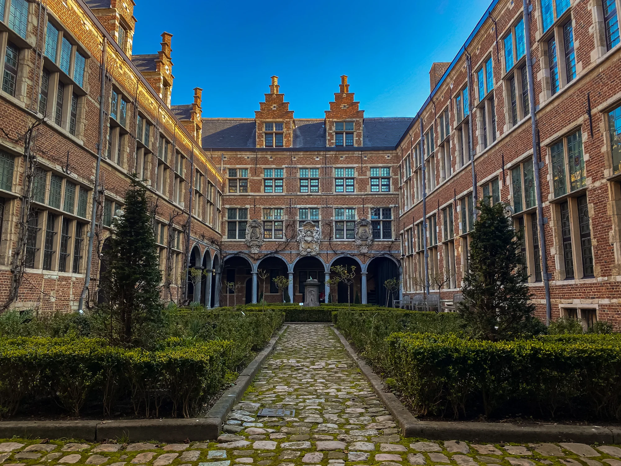 Inner courtyard of the Plantin-Moretus Museum, featuring historic architecture and green gardens.