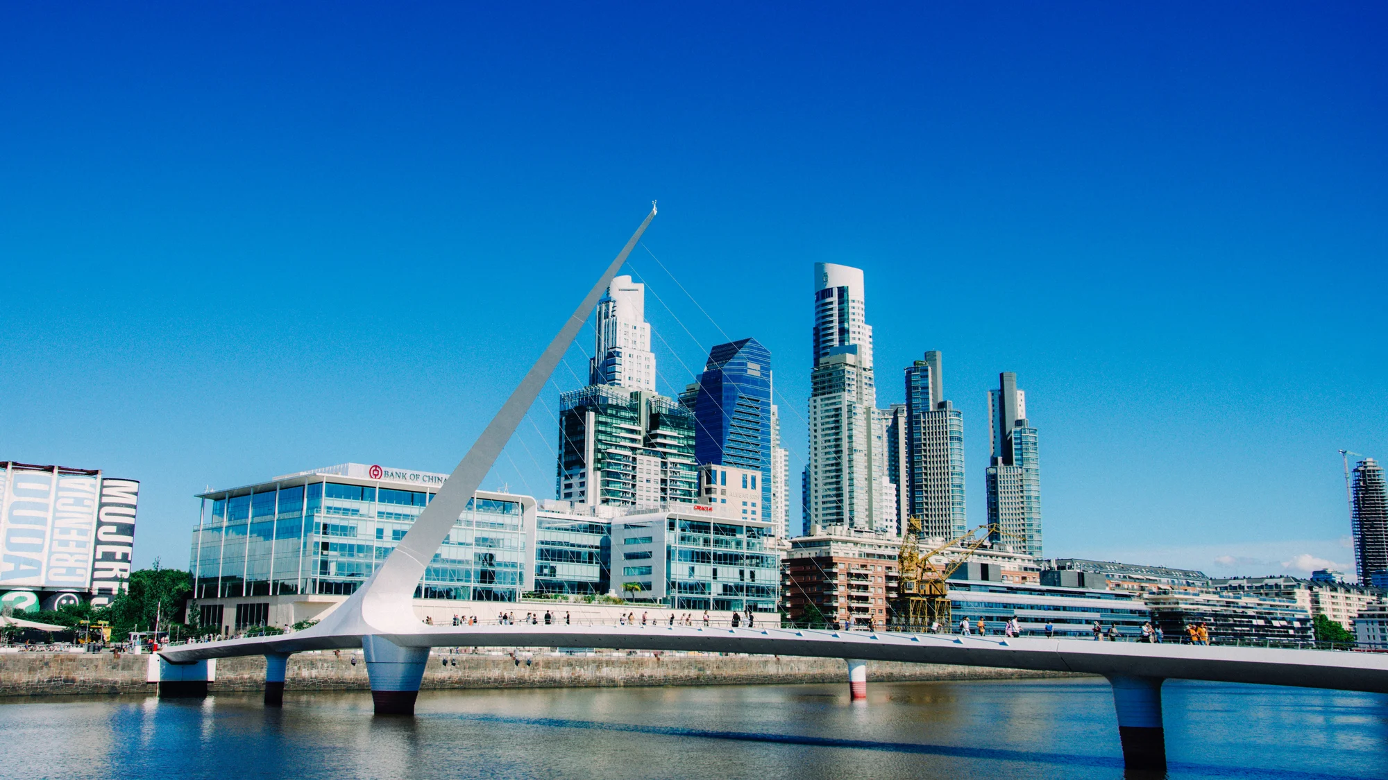 Women's Bridge, an architectural icon in Puerto Madero, Buenos Aires, with tall buildings and a clear blue sky.