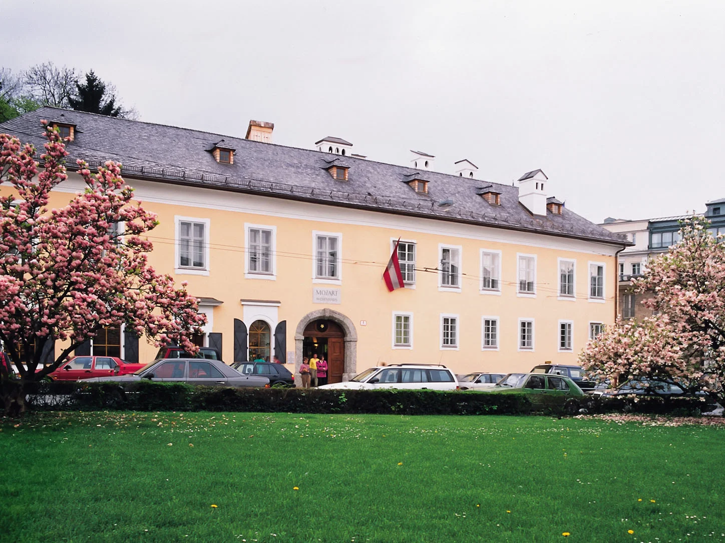 Facade of Mozarts Wohnhaus in Salzburg, with blooming magnolias in the foreground.