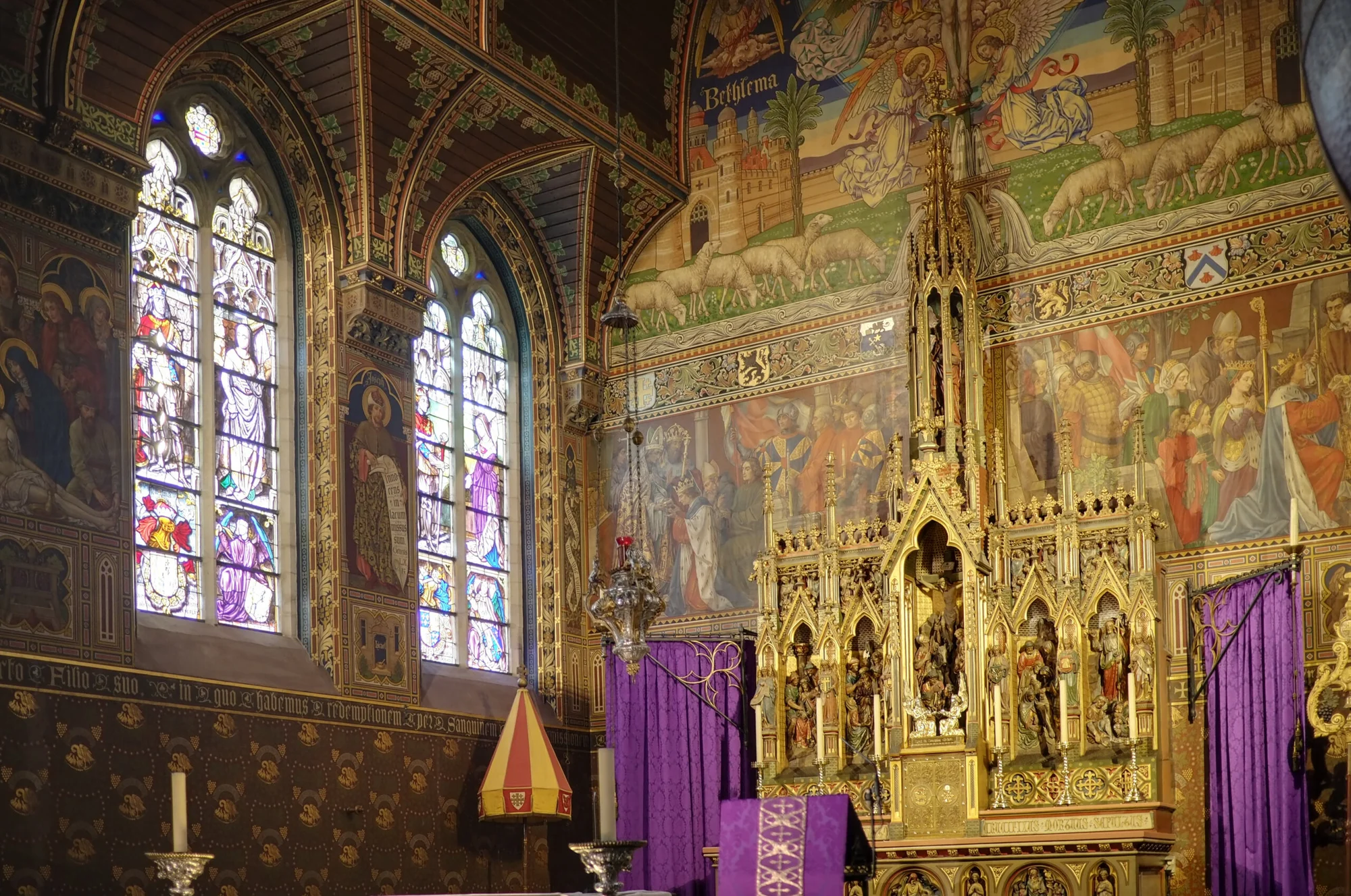 Interior of the Basilica of the Holy Blood in Bruges, featuring vibrant stained glass windows and an elaborate altar.