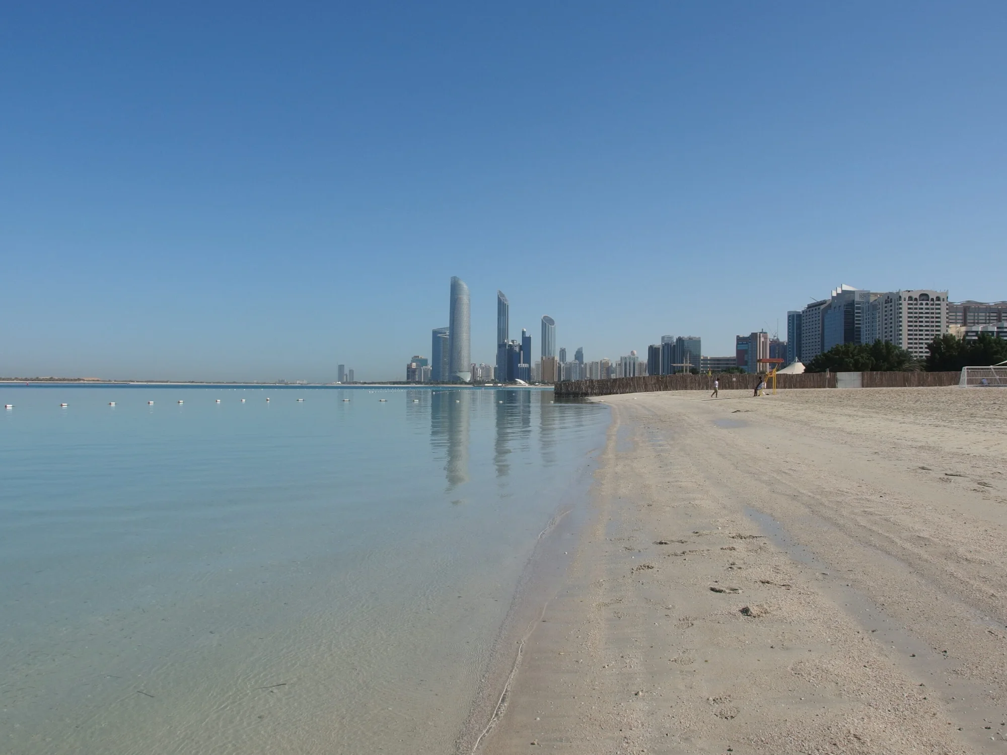 Corniche Beach in Abu Dhabi with calm waters and the city's skyline in the background.