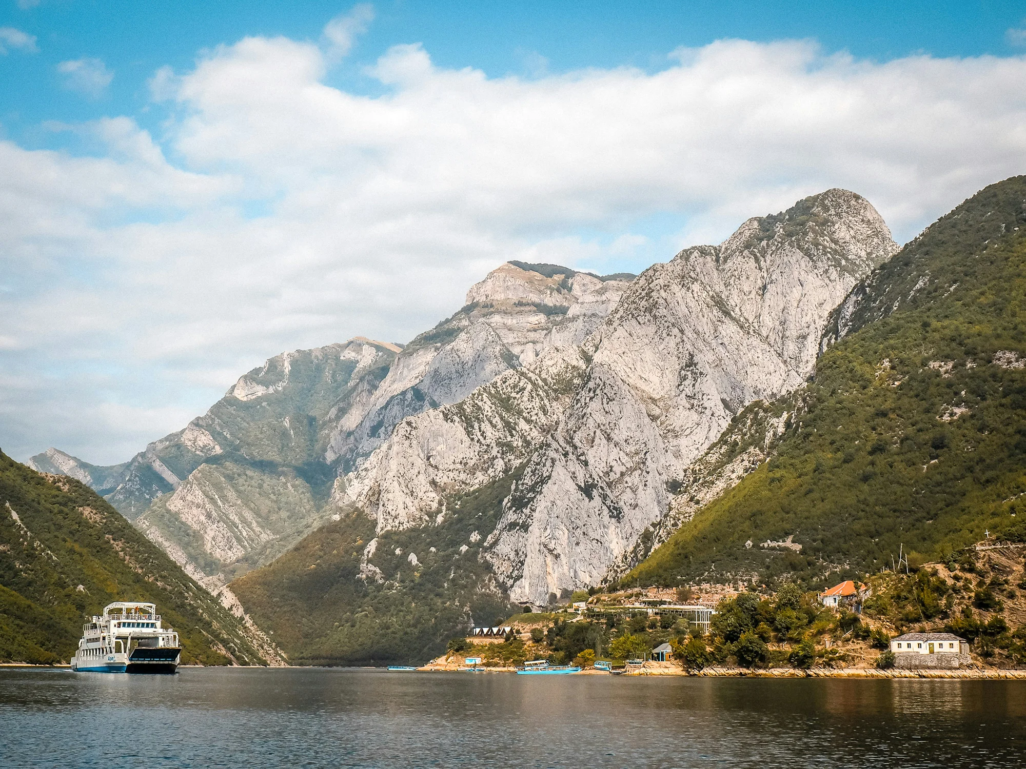 Komani Lake in Shkoder, Albania, featuring a tourist ferry and breathtaking mountain scenery.