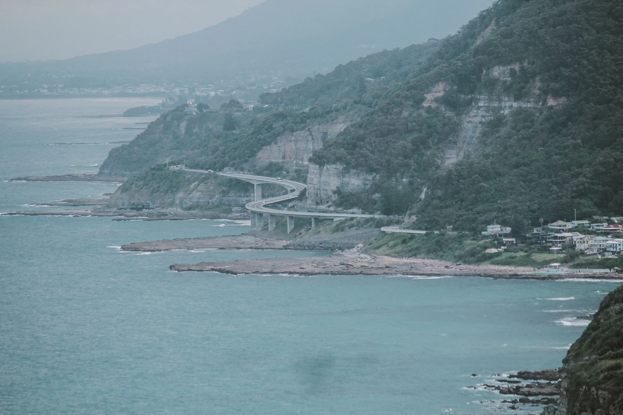 Sea Cliff Bridge in Wollongong, Australia, with mountains and ocean in the background.