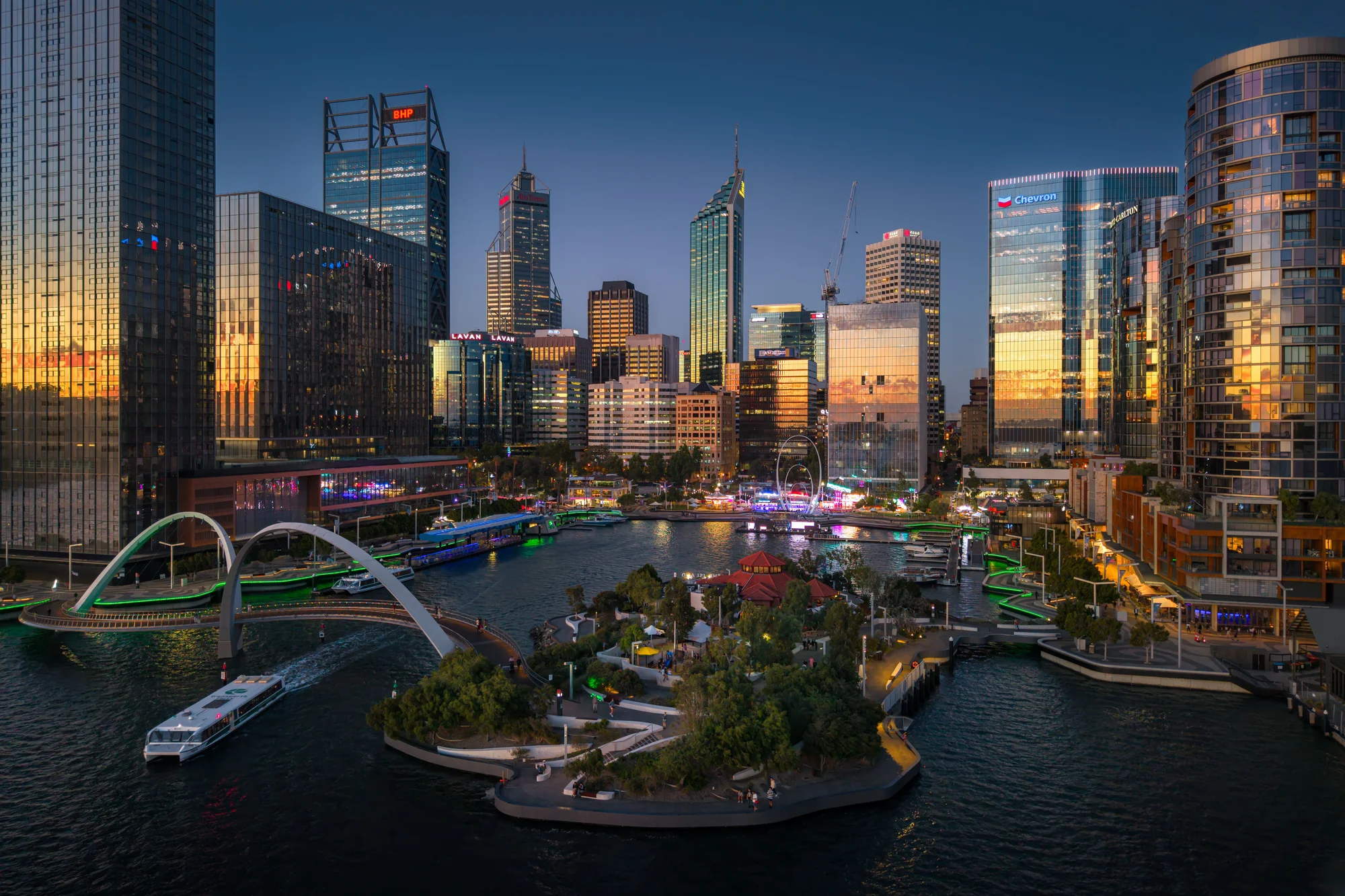 Image of Perth city center, Australia, glowing in sunset light with bridges and modern architecture.