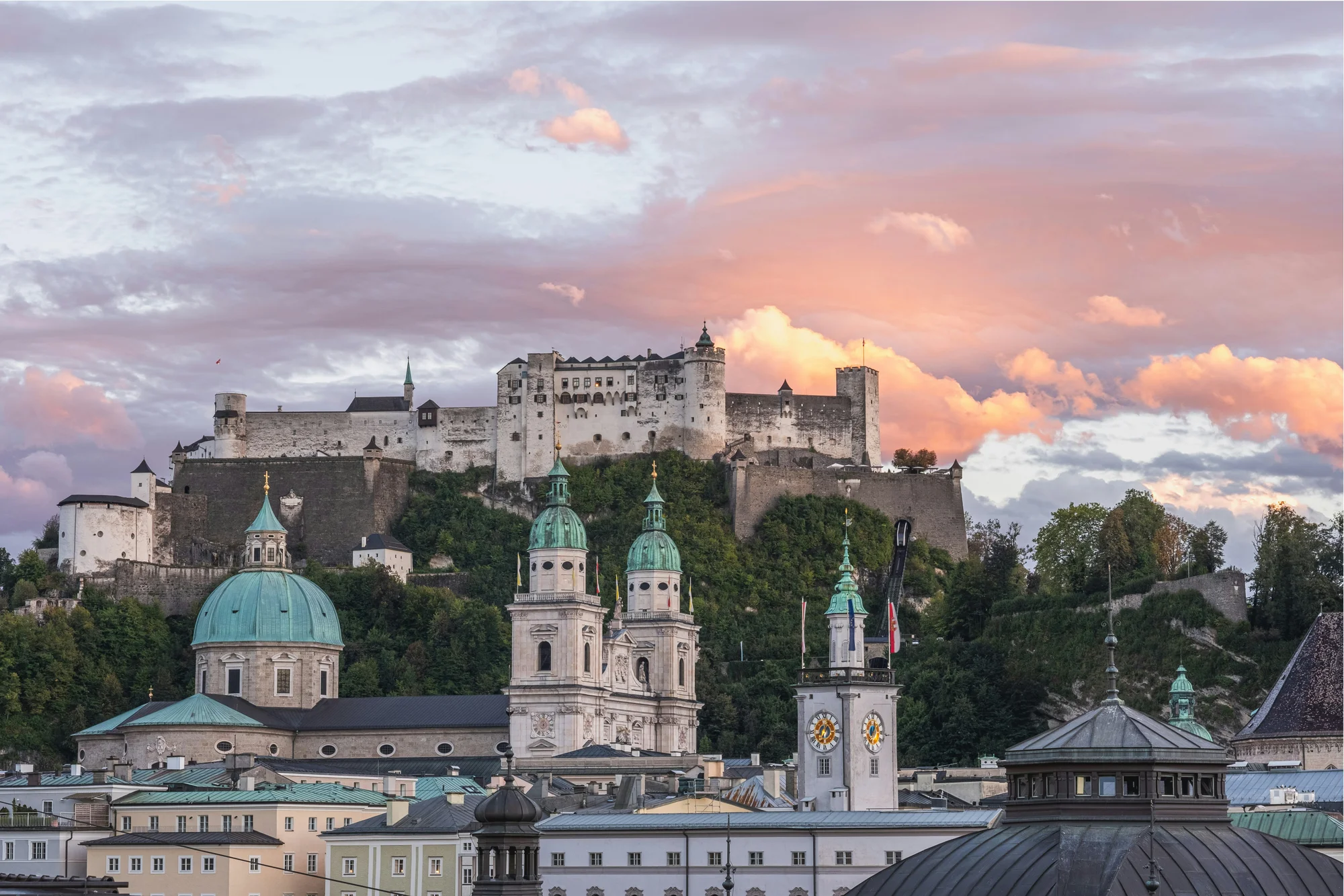 Hohensalzburg Fortress in Salzburg, Austria, viewed at sunset with a colorful sky.