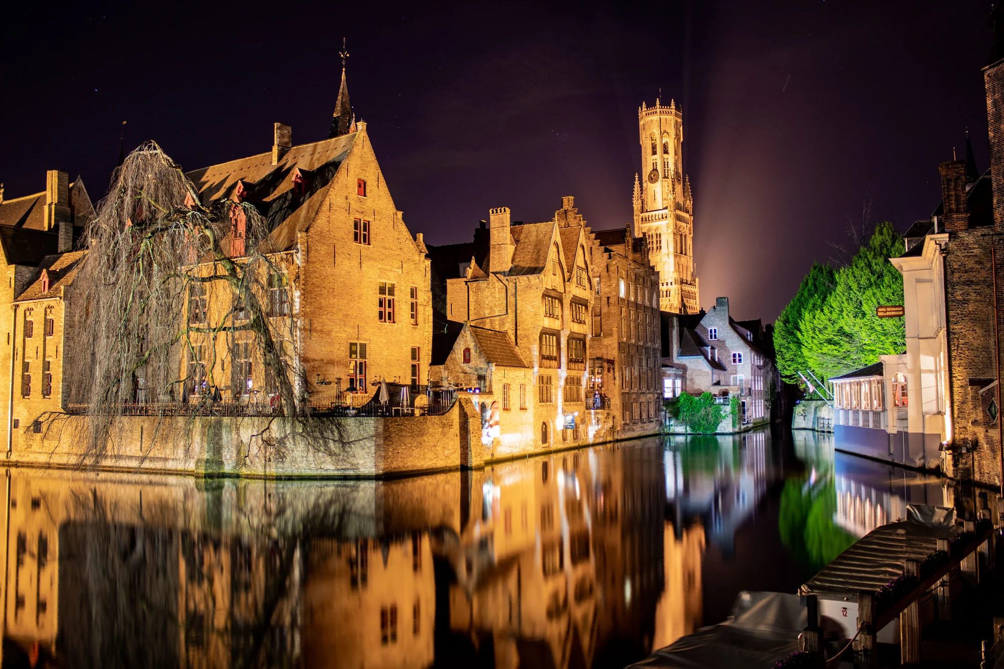 Nighttime scene of Bruges, Belgium, with lit canals and buildings.
