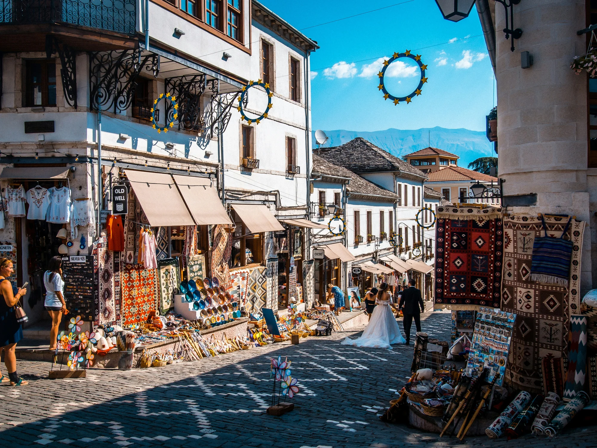 Vibrant street in Gjirokastër with traditional shops and picturesque white houses.
