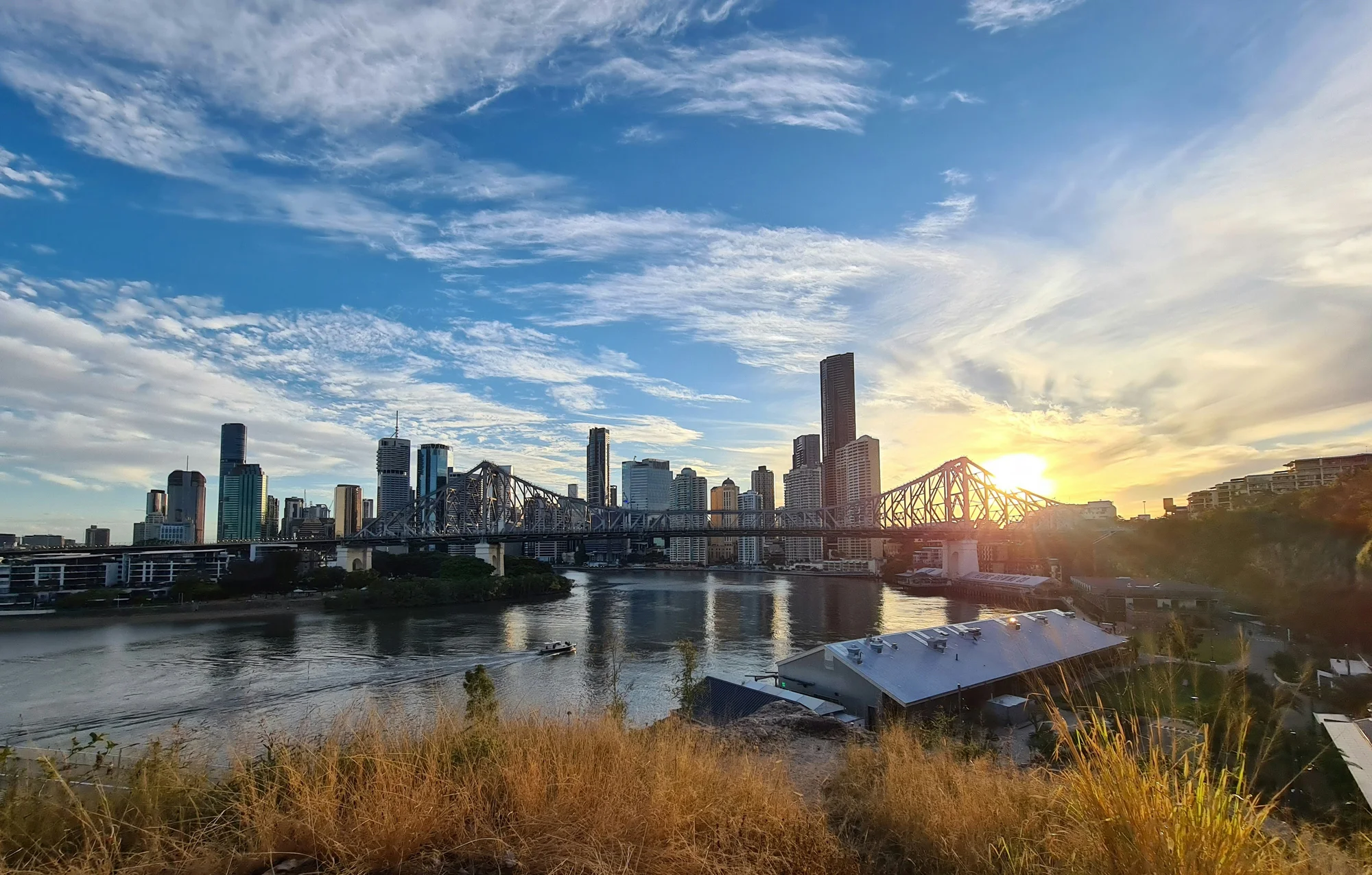 Sunset view of Brisbane city skyline with Story Bridge and Brisbane River.