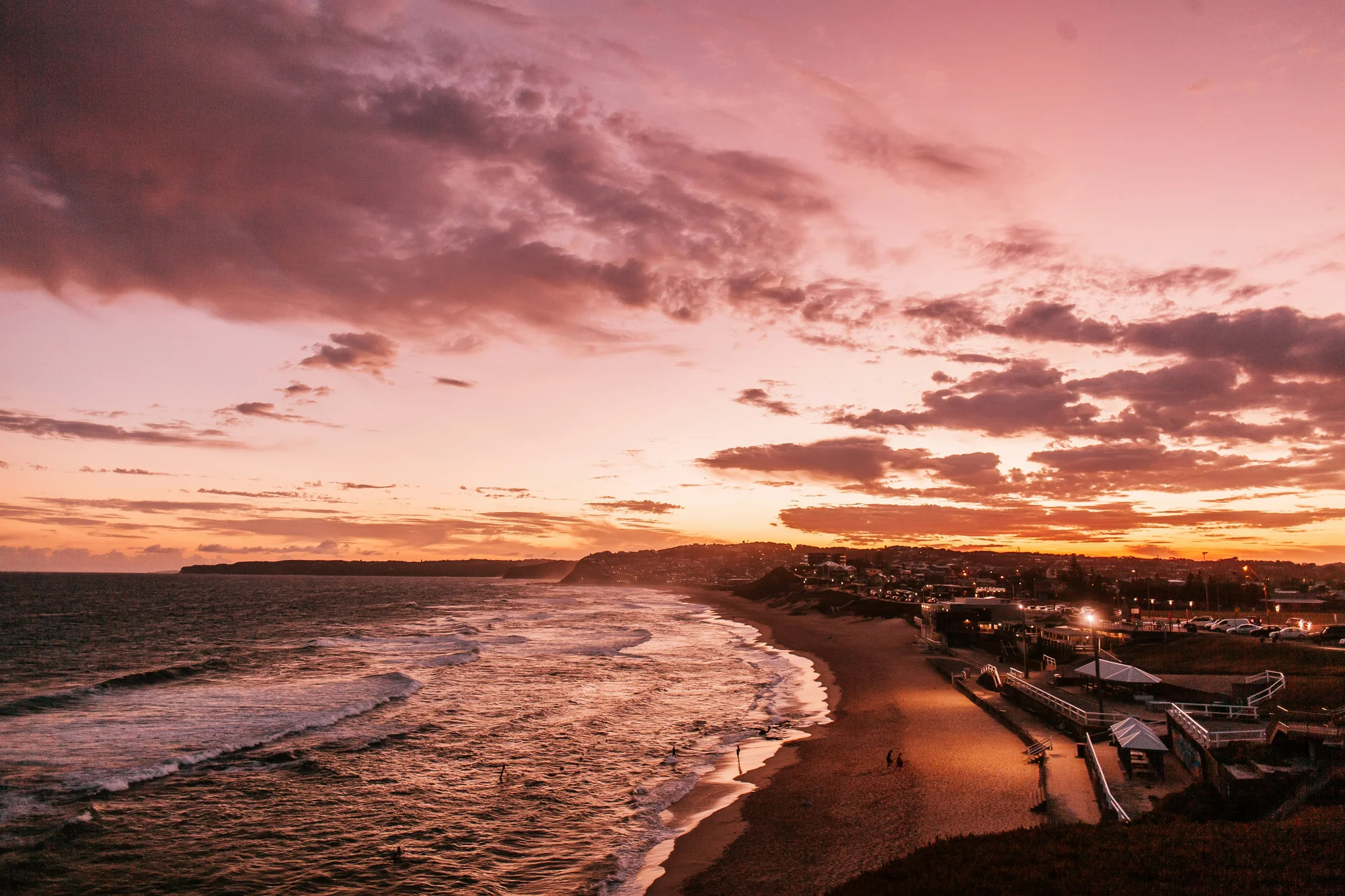 Sunset at Newcastle Beach, Australia, with calm waves and a colorful sky.