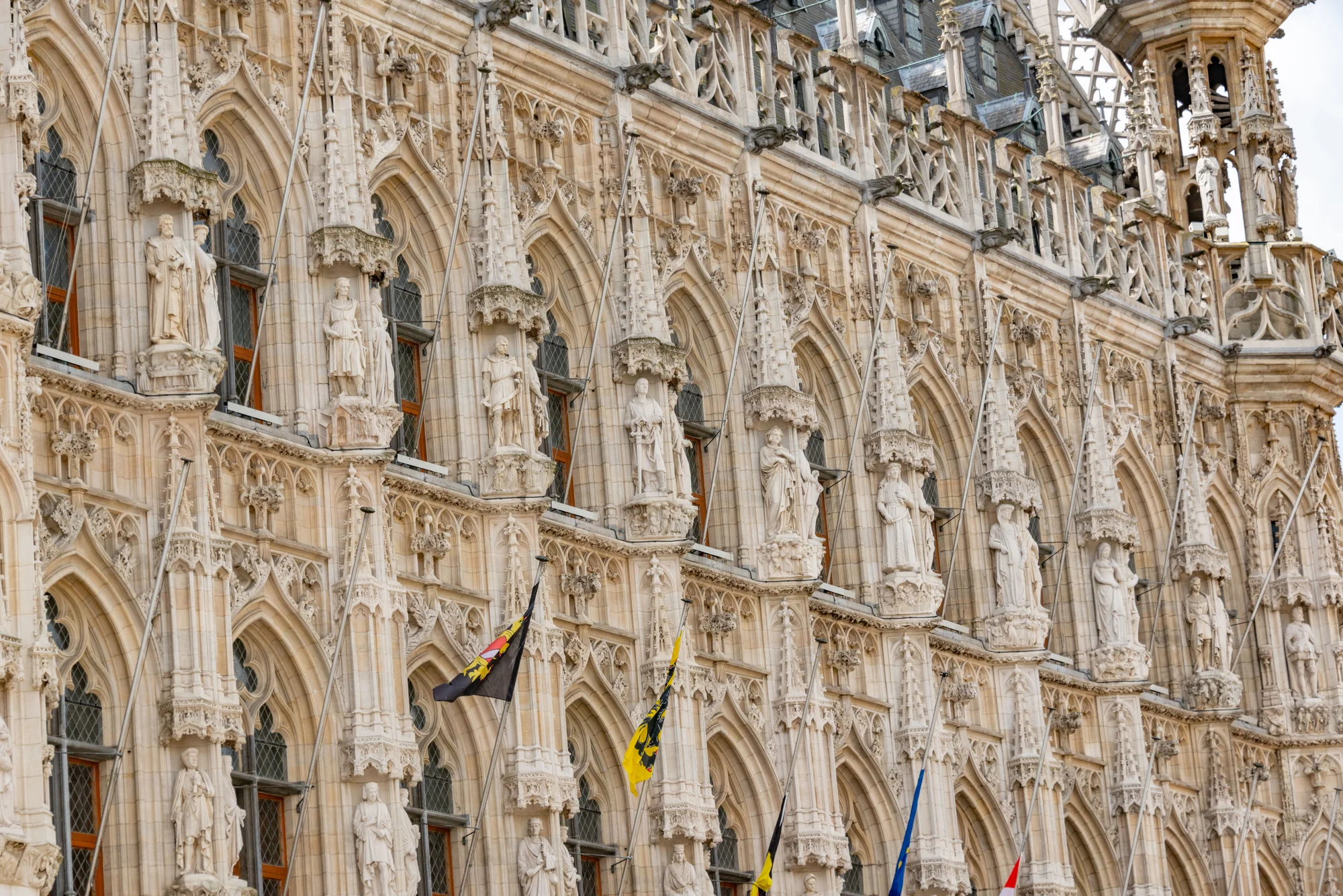 Detailed Gothic facade of the Town Hall in Leuven, Belgium, featuring intricate sculptures.