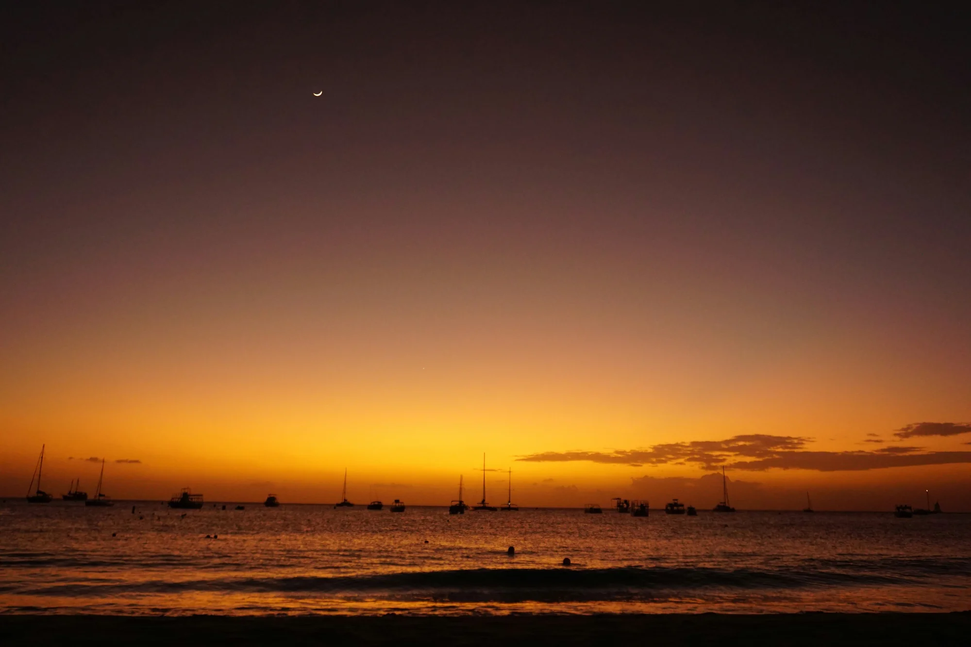 Sunset on the beach in Bridgetown, Barbados, with yachts in the distance.
