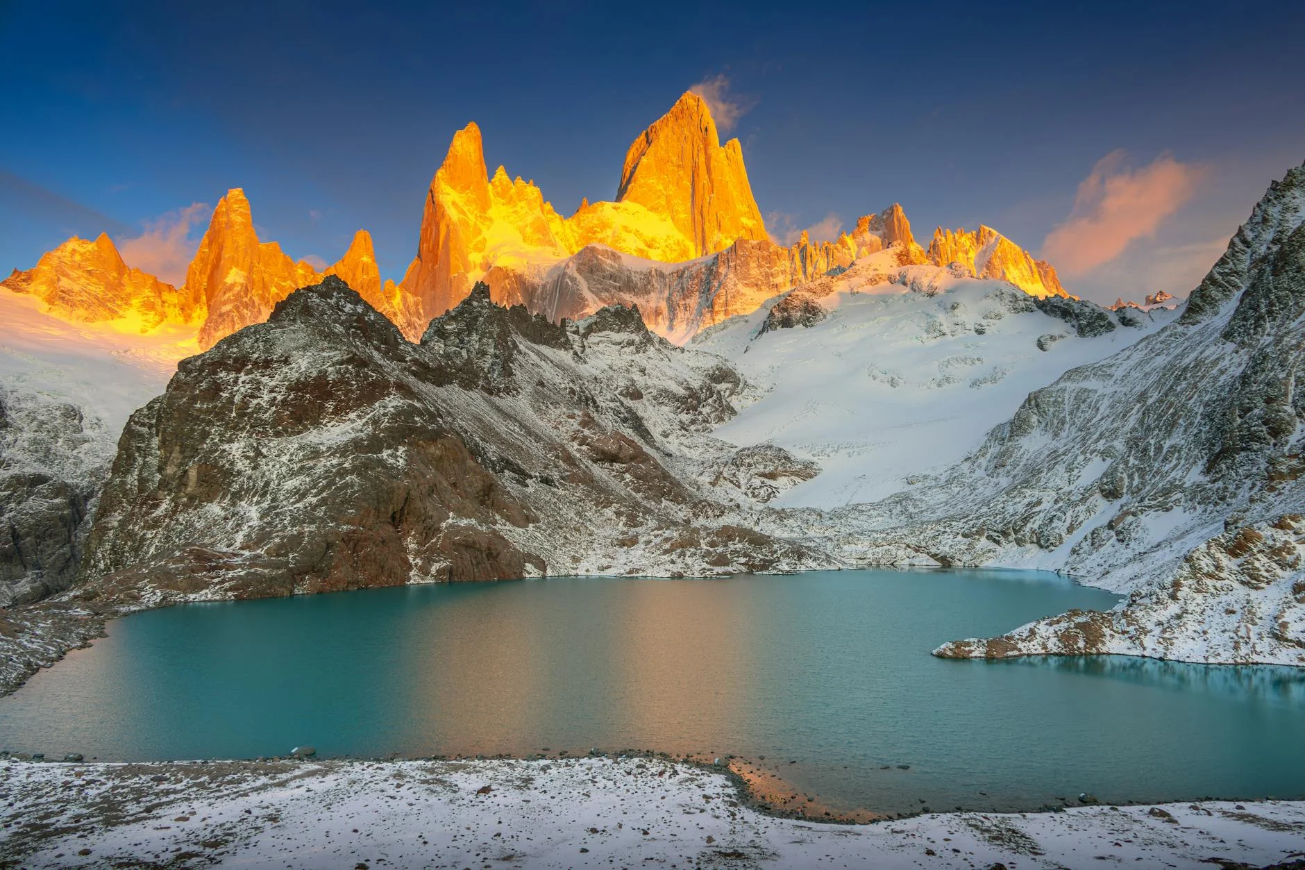 Fitz Roy mountains lit by sunrise with a clear lake in the foreground, Patagonia, Argentina.